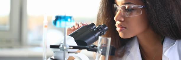 Black woman scientist student chemist in protective Black woman scientist student chemist in protective goggles are conducting research using microscope for bacterial contamination of water to search for vaccine to treat diseases in medicine. african american scientist stock pictures, royalty-free photos & images