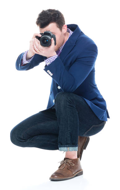 istock Side view of handsome man crouching while holding DSLR camera 1073768962