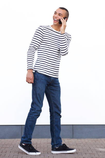 istock young man walking and talking with cellphone by white wall 1073775352