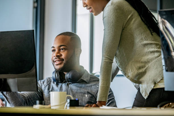 istock Young businessman using computer female colleague watching 1073787936
