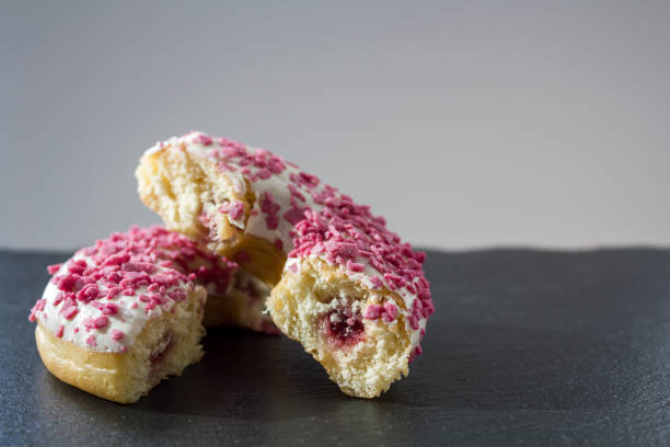 istock Donut with white frosting and pink sprinkles cut in half 1073788344