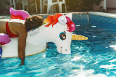 lazy woman relaxing on inflatable unicorn in pool