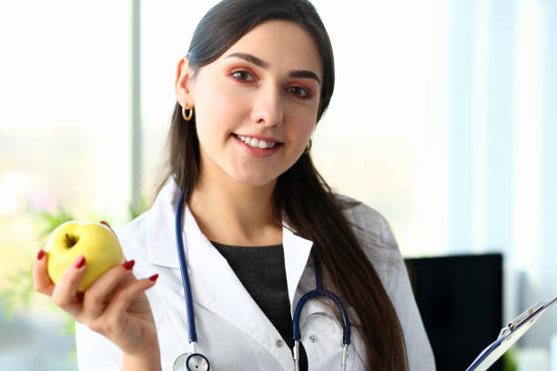 istock Doctor holding green apple with copy space on blue 1073791172
