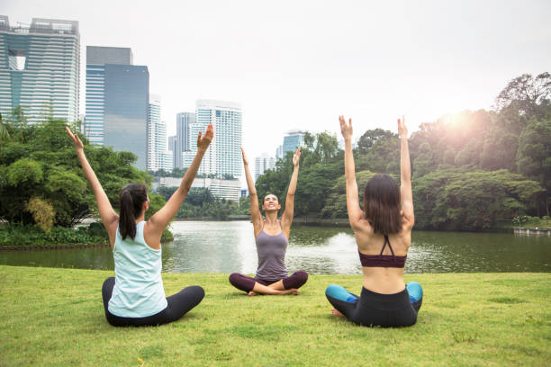 Fit friends with hands raised sitting near lake