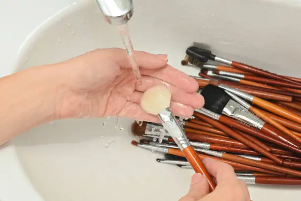 woman is washing dirty makeup brush