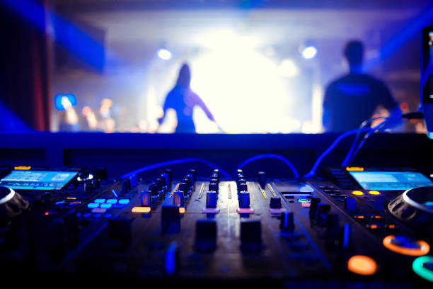 istock DJ turntable console mixer controlling with two hand in concert nightclub stage. 1073818976