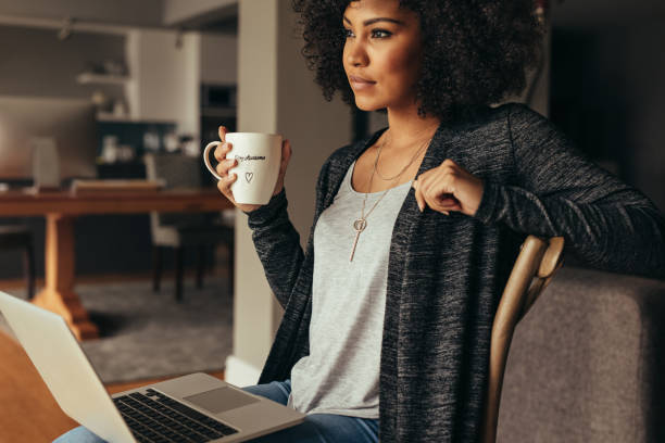 istock Thoughtful female having coffee while working on laptop at home 1073829644