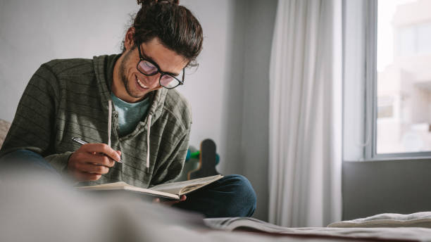 istock Smiling student studying for exam sitting on bed 1073830098