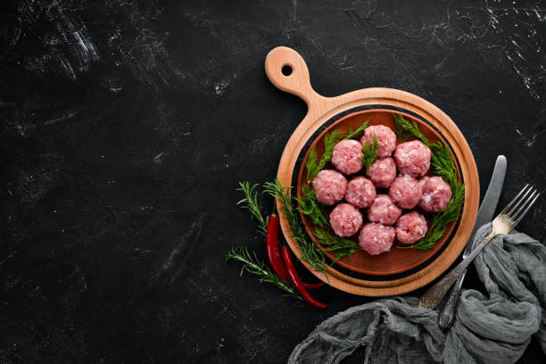 istock Raw meat balls. On a black stone background. Top view. Free copy space. 1073831374