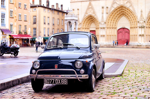 January 21, 2018 - Lyon, Auvergne-Rhône-Alpes, France. Vintage Fiat 500L in front of Cathedral Saint Jean Baptiste. Cars in Lyon. Lyon streets. Lyon architecture. French cities. Winter in Lyon, France