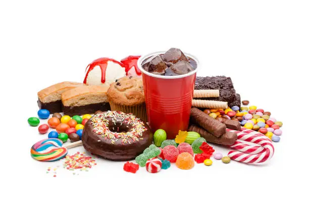 High angle view of a large group of multicolored products with high sugar level shot on white background. Food included in the composition are candies, donuts, chocolate bar, a glass of soda, ice cream, muffin and bakery items. High key DSRL studio photo taken with Canon EOS 5D Mk II and Canon EF 100mm f/2.8L Macro IS USM.
