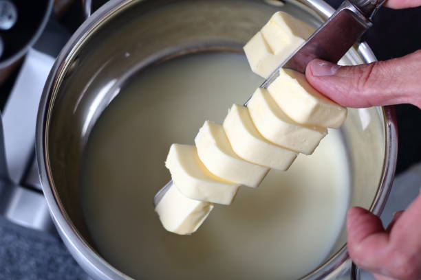 istock Adding diced butter into pan with sweetened condensed milk. Making Boston Banoffee Pie. 1073868508
