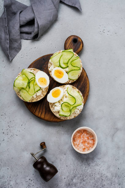 istock Cucumber, egg and curd cheese sandwiches on gray concrete background. Top view. 1073883872