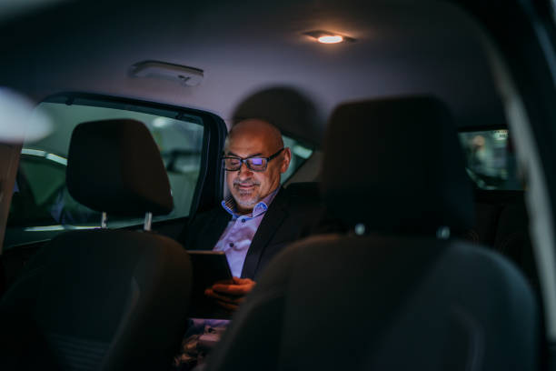 istock Senior adult sitting on backseat and using tablet at night. 1073907126