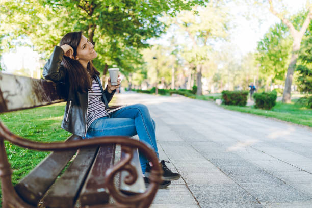 istock Young woman drinking coffee in a park 1073907648