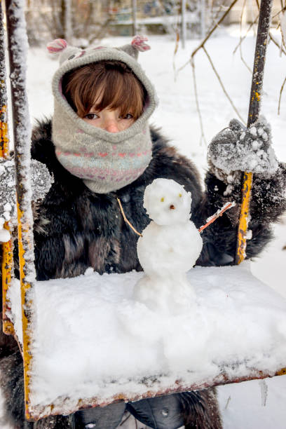 istock happy girl and snowman 1073918512