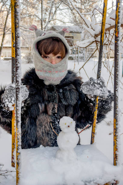 istock happy girl and snowman 1073918538