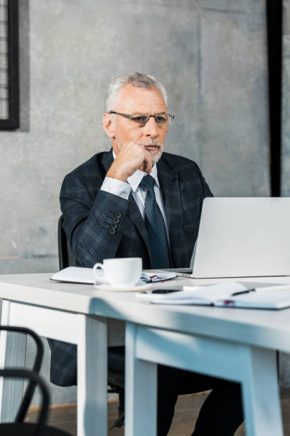 istock handsome middle aged businessman working at laptop in office 1073919330