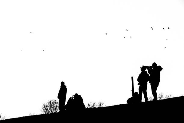 A black and white image of a silhouetted photographer on a hill.