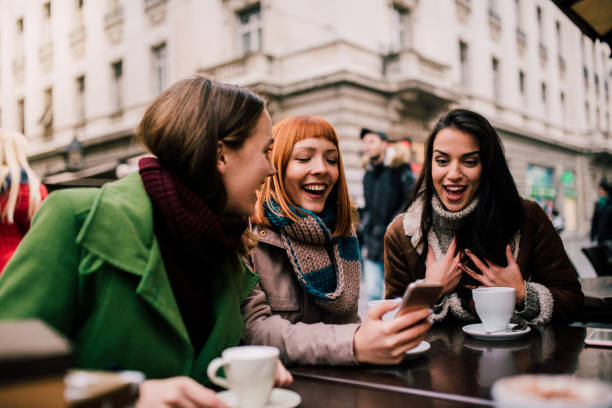 istock Smiling friends looking at mobile phone 1073928524