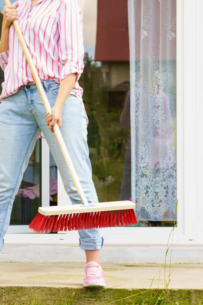 istock Woman using broom to clean up backyard patio 1073938710