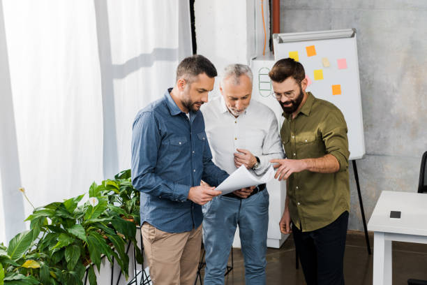 istock three professional businessmen discussing blueprint in office 1073952342