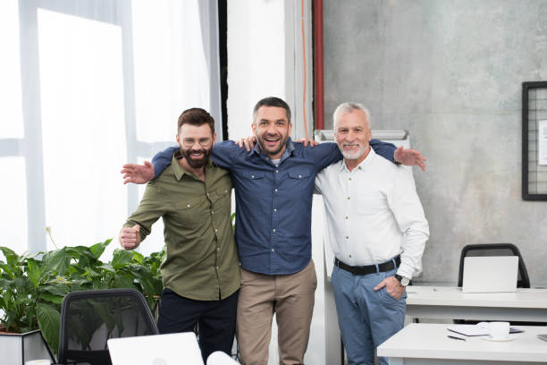 istock smiling handsome businessmen hugging and looking at camera in office 1073952412