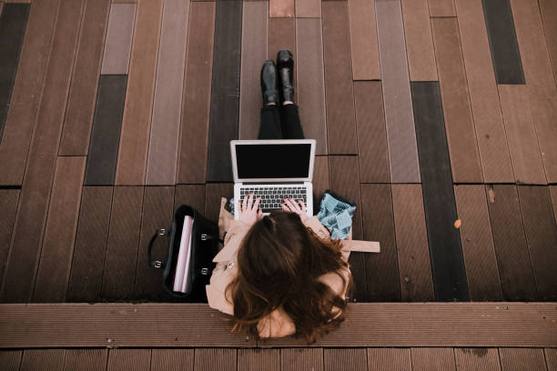 jovem mulher sentada no parque público com laptop - above 21 - fotografias e filmes do acervo