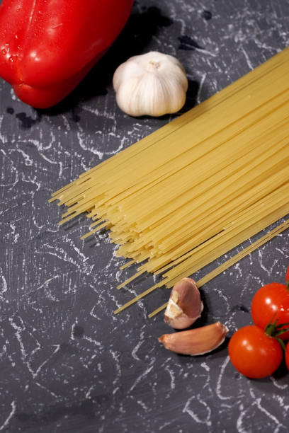 istock Scattered pasta, garlic, tomatoes, on grey background 1073965468
