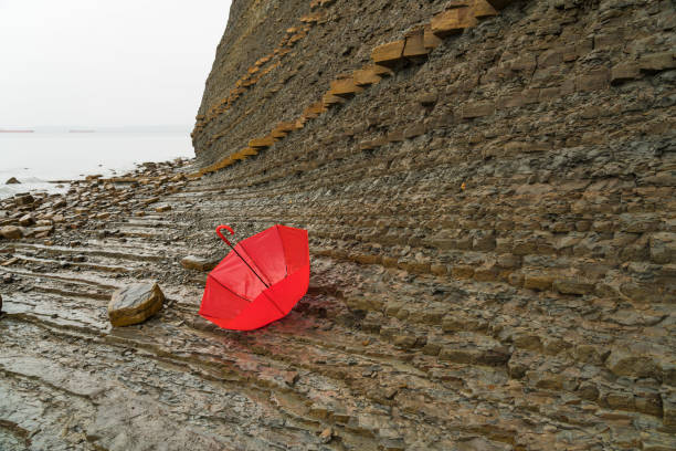 czerwony parasol na klifie - osadowa ściana skalna - extreme terrain eroded snow landscape zdjęcia i obrazy z banku zdjęć