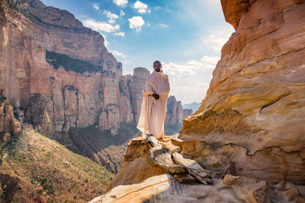monk stands at abuna yemata guh monolithic church in hawzen tigray region ethiopia - etiopia i imagens e fotografias de stock