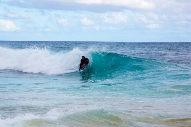 mann läuft in die wellen am strand - surfing men hawaii islands wave stock-fotos und bilder