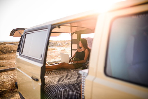 Freelance woman working from the van while taking a road trip