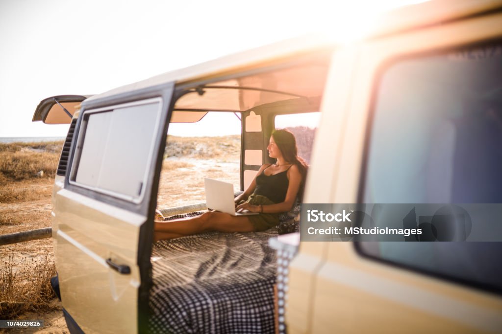 Woman using laptop. Freelance woman working from the van while taking a road trip Travel Stock Photo