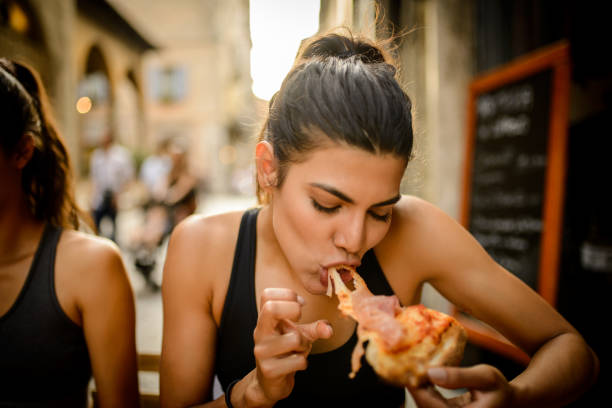 Two sporty woman eating pizza after workout