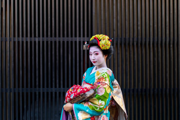 istock Maiko Apprentice Geisha standing in front of black grid wall 1074030462