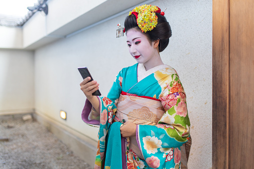 Maiko Apprentice Geisha using smart phone during short break