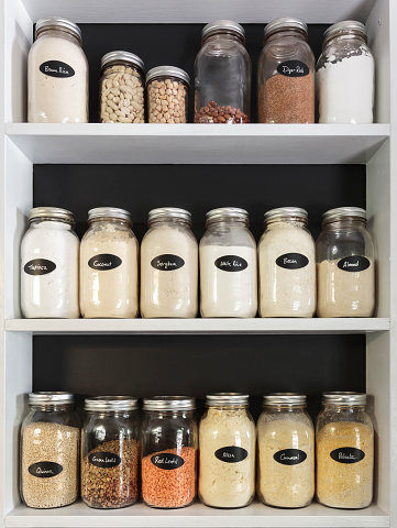 Jars of Flours and grains on white shelves in pantry