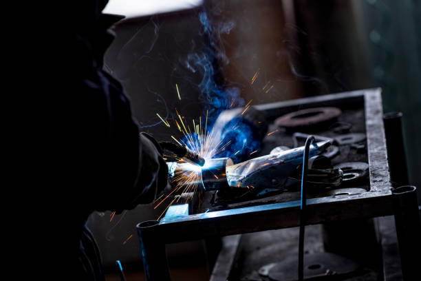 istock Male worker wearing protective gloves while repairing car exhaust pipe with welding machine 1074032744