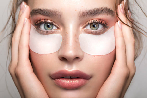 Woman beauty Closeup studio shot of a beautiful young woman with freckles skin and under eye mask posing against a grey background one eyed stock pictures, royalty-free photos & images