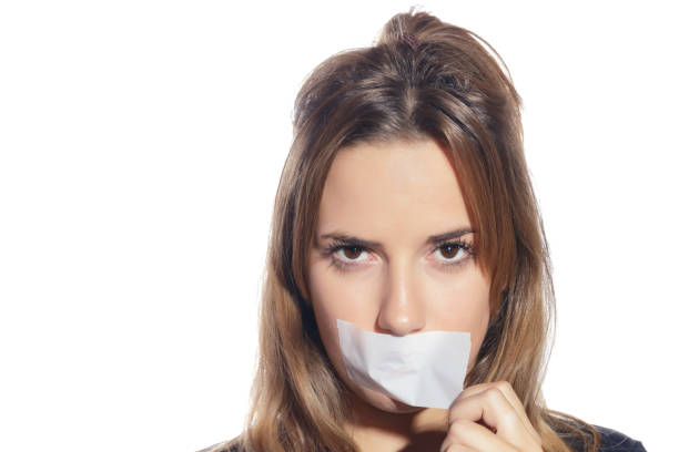 Blonde woman silenced with tape, removing it. Blonde woman silenced with tape, removing it and finally free. Isolated, over a white background. copyright free medical stock pictures, royalty-free photos & images