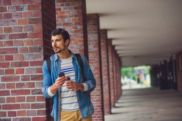 istock casual young man using his phone outdoors 1074047680