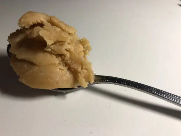 Closeup of raw sugar cookie dough layered on a silver spoon, white background