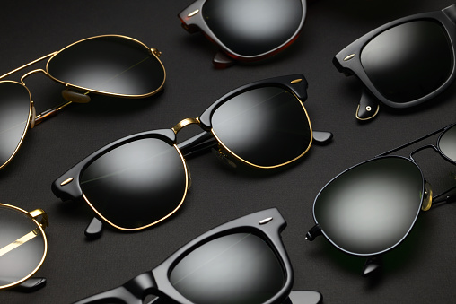 Set of old-fashioned sunglasses arranged in a row on black background