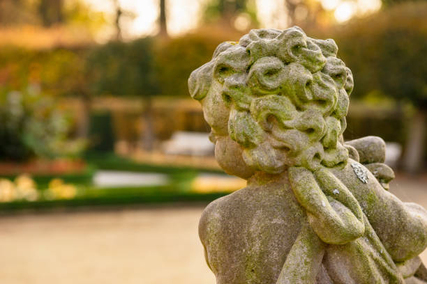 statua dell'angelo di pietra in giardino. statua dell'angelo custode alla luce del sole come simbolo d'amore in giardino. - sculpture statue cupid gold foto e immagini stock