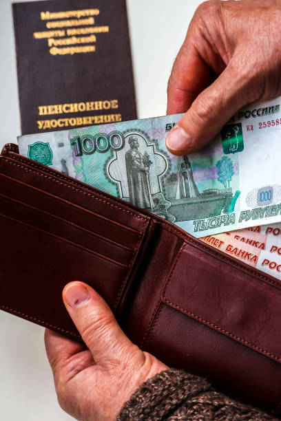 istock Woman's hands holding wallet with russian rubles, russian pension certificate in background. 1074100232