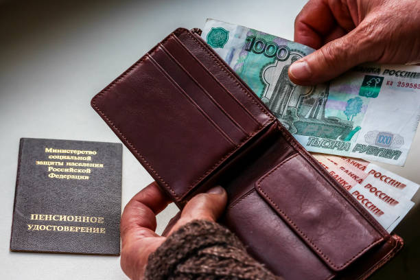 mani della donna che tiene portafoglio con rubli russi, certificato di pensione russo sullo sfondo. - pension foto e immagini stock