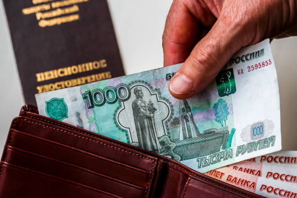 istock Woman's hands holding wallet with russian rubles, russian pension certificate in background. 1074100300
