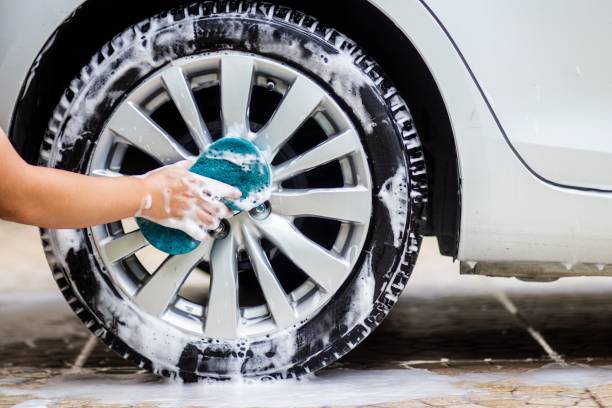 esta imagen es una imagen de limpiar el coche con un microfibra azul por las manos. concepto de lavado de coches. - tire rim fotografías e imágenes de stock