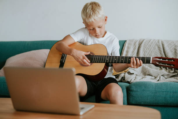 istock Boy learning to play guitar through a video call with his teacher 1074126170